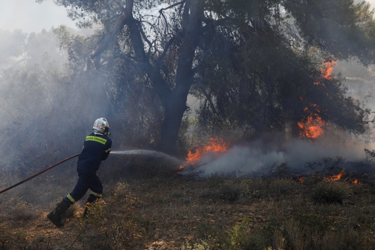 فرق الإطفاء تحاول احتواء النيران في غابات باليني قرب أثينا (رويترز)